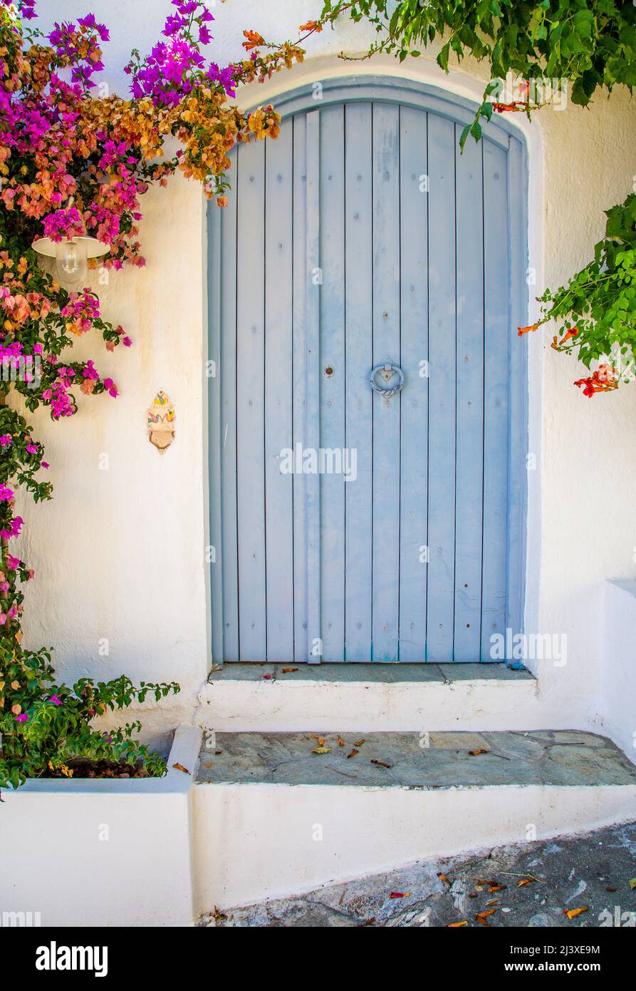 Blaue Tür in einer weißen Wand mit Bouganvillea auf der Insel Alonnisos auf den griechischen Sporaden Stockfoto