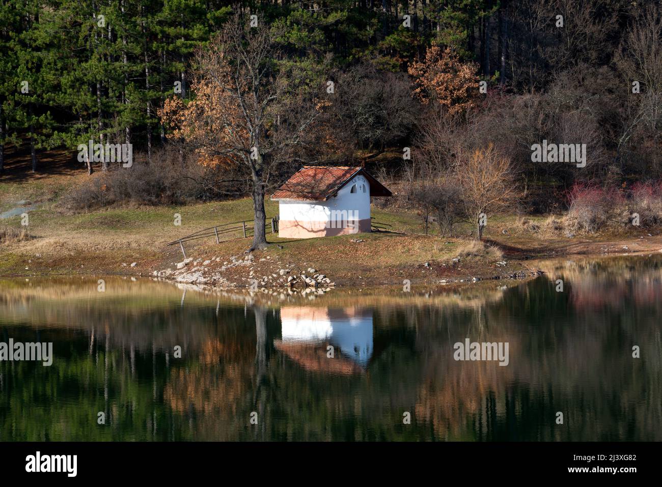 Schöne Herbst Berglandschaft und Reflexion im Wasser der Kapelle "St. Petka' (St. Paraskeva) und Waldbäumen am Ufer des Incredi Stockfoto