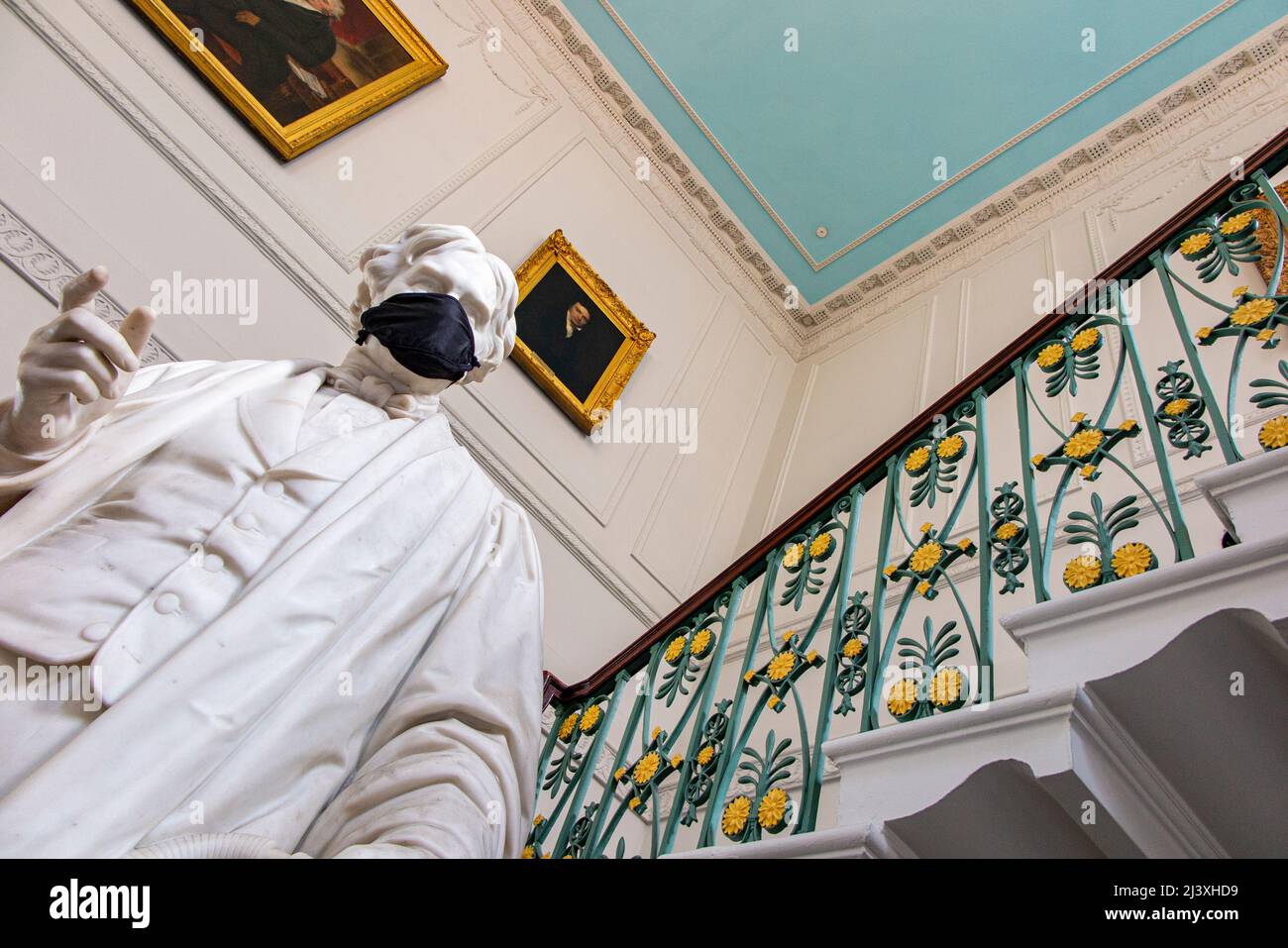 Die Haupttreppe an der Royal Institution of Great Britain in Mayfair und eine Statue von Michael Farraday tragen während der COVID-Pandemie 19 eine Gesichtsmask Stockfoto