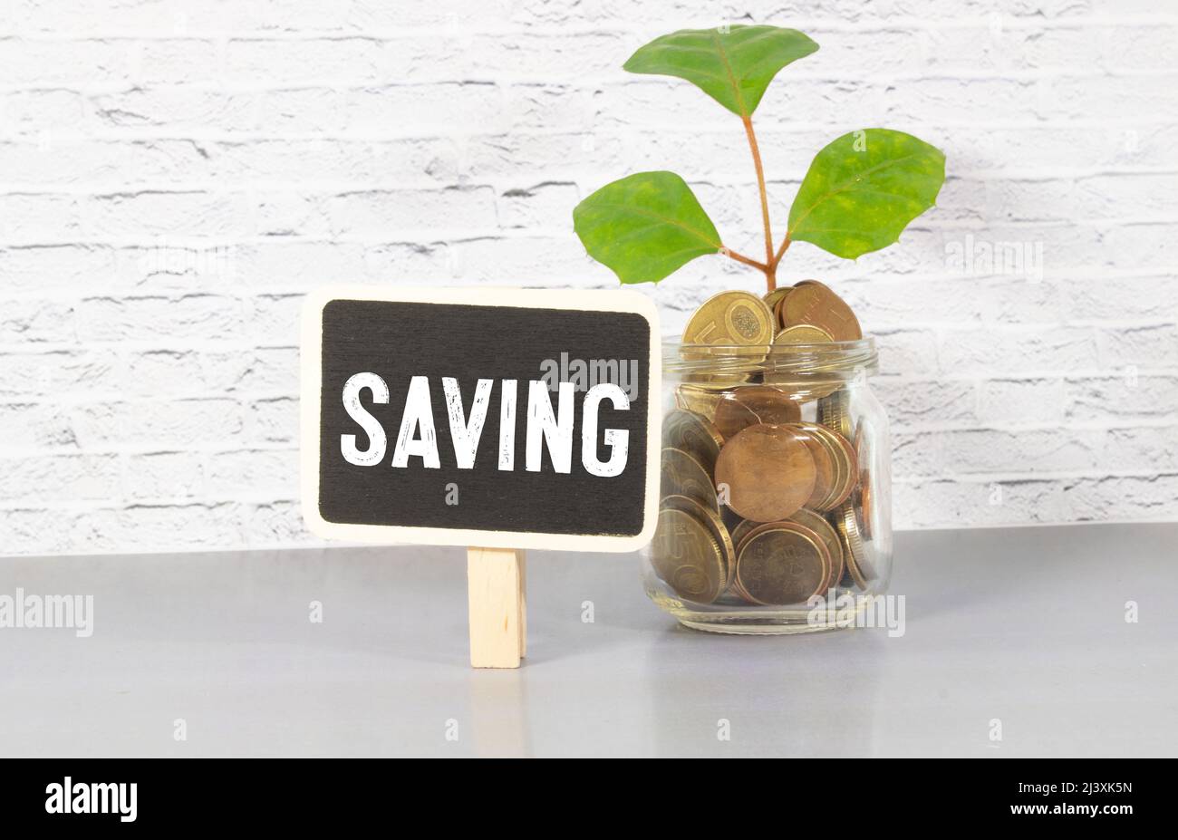 Ein Mann steckt Geld in ein Glas mit dem Wort Rechnungen. Zahlungskonzept für Stromrechnung. Gehäuse, Strom, Wasser Rechnungen. Konto, Geschäft und Finanzen. S Stockfoto