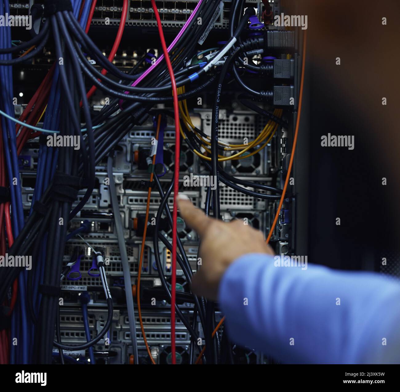 Manchmal geht es nur darum, Punkt A mit Punkt B zu verbinden. Kurzer Blick auf einen nicht erkennbaren männlichen IT-Support-Agenten, der in einem dunklen Netzwerkserver arbeitet Stockfoto