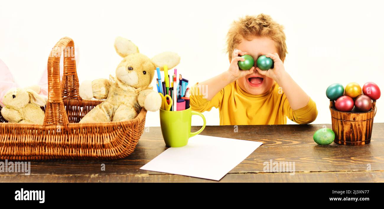 Niedlicher kleiner Junge, der die Augen mit bunten Ostereiern bedeckt. Osteraktivitäten für Kinder. Stockfoto