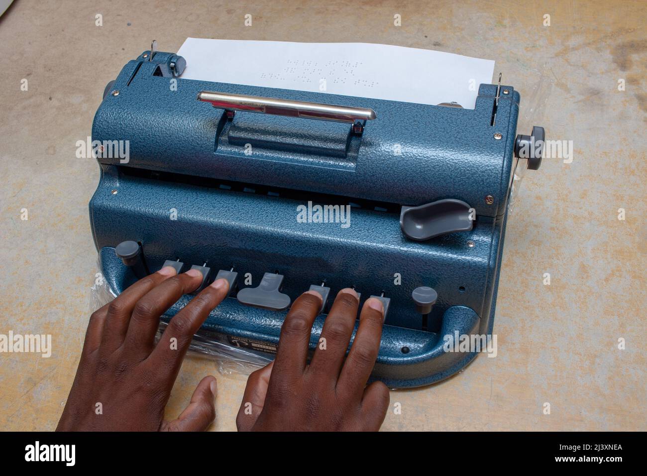 Nahaufnahme einer schwarzen blinden Person, die auf einem Braille-Drucker tippt Stockfoto