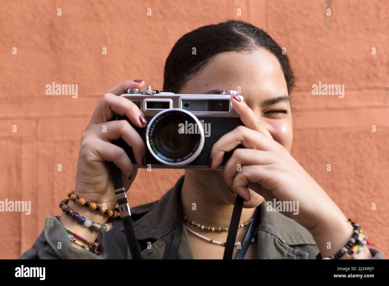 Nahaufnahme eines jungen Mädchens mit gemischter Rasse, das mit ihrer Kamera im Freien fotografiert. Stockfoto