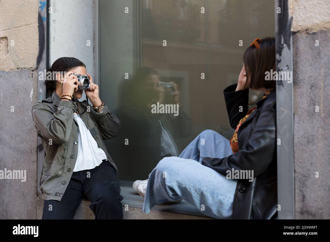 Gemischtes Mädchen, das ein Foto von einem anderen Mädchen auf der Straße fotografiert. Multiethnische Freunde, die Spaß haben. Stockfoto