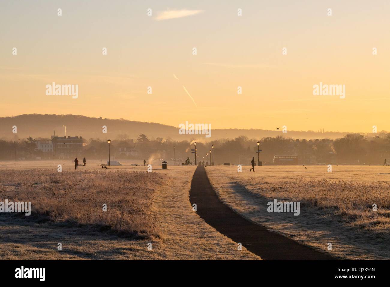 Ein Blick auf Blackheath Common im Winter bei einem warmen Sonnenuntergang. Man kann sehen, wie die Menschen ihren Morgen genießen. Stockfoto