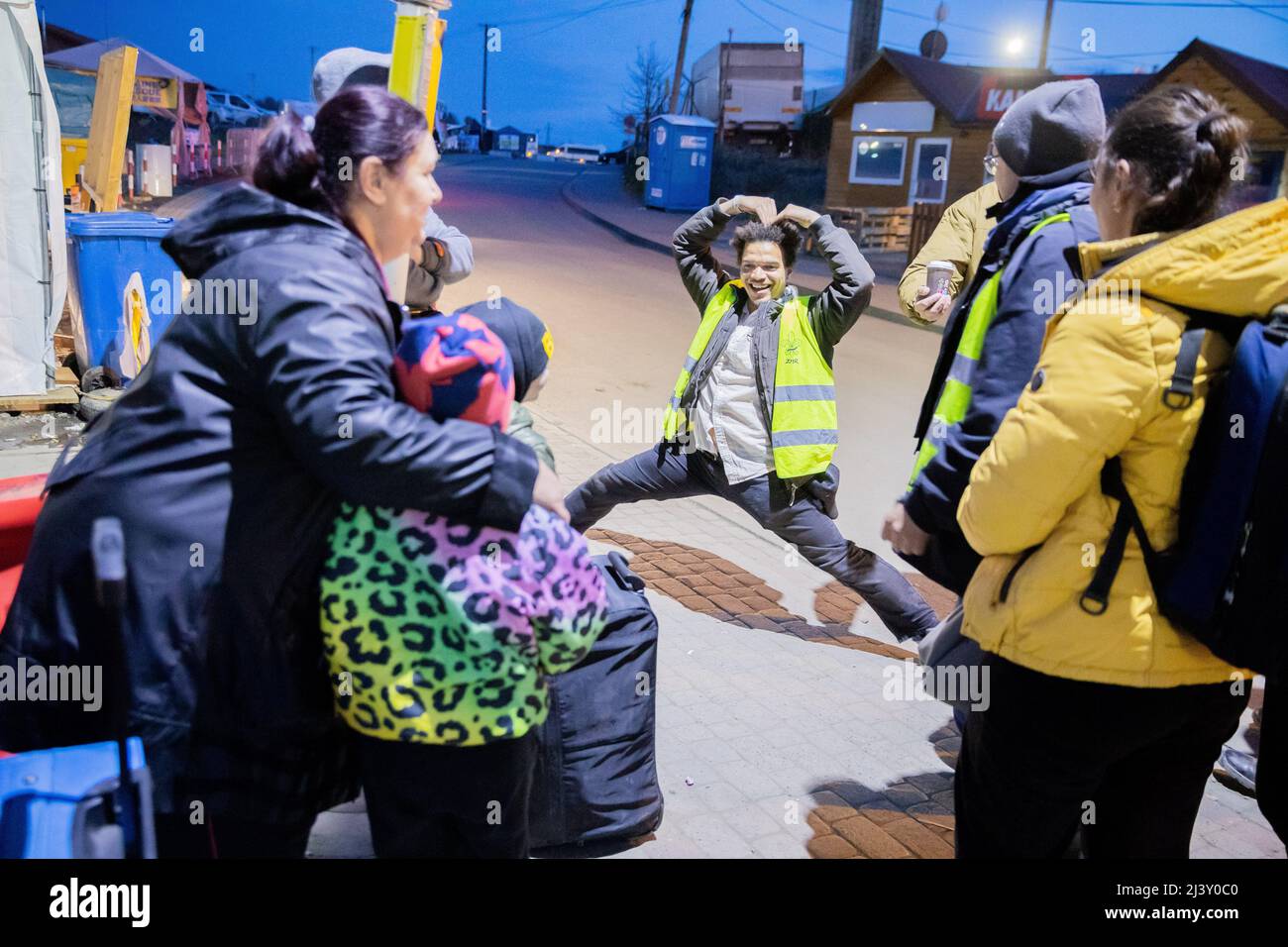 Przemysl, Polen. 10. April 2022. Lance Davis, Freiwillige aus den USA, tanzt für Unterhaltung vor Flüchtlingskindern, während sie auf einen Bus am Grenzübergang Medyka auf der polnischen Seite auf der anderen Seite der ukrainischen Grenze warten. Quelle: Christoph Soeder/dpa/Alamy Live News Stockfoto