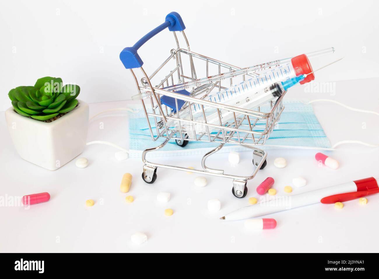 Einkaufswagen und Medizin. Teure Medizin. Warenkorb mit Blasen mit Pillen und Medikamentenflaschen auf blauem Hintergrund. Stockfoto