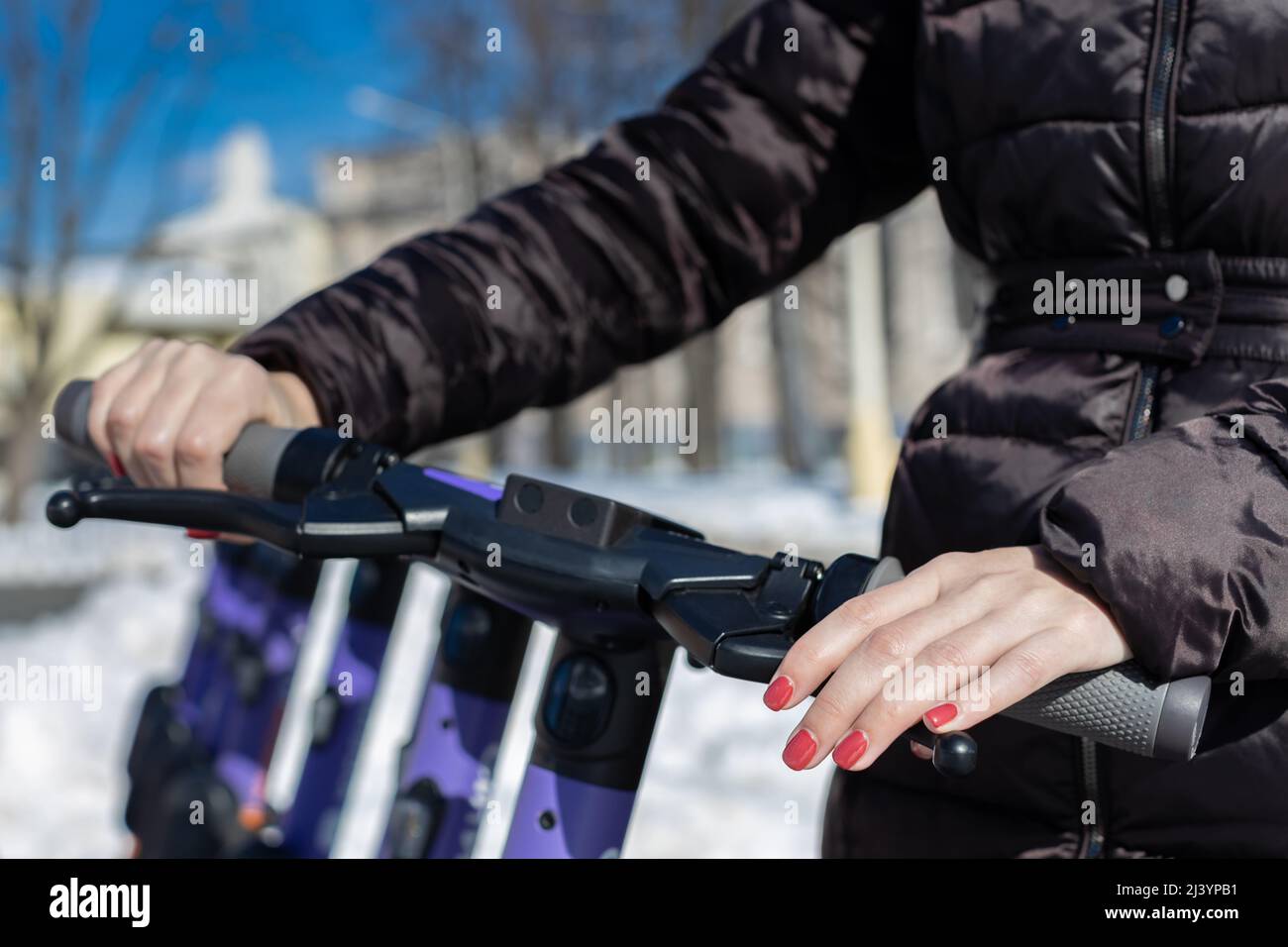 Eine Frauenhand drückt den Gasgriff und die Bremse des Rollers. Hochwertige Fotos Stockfoto