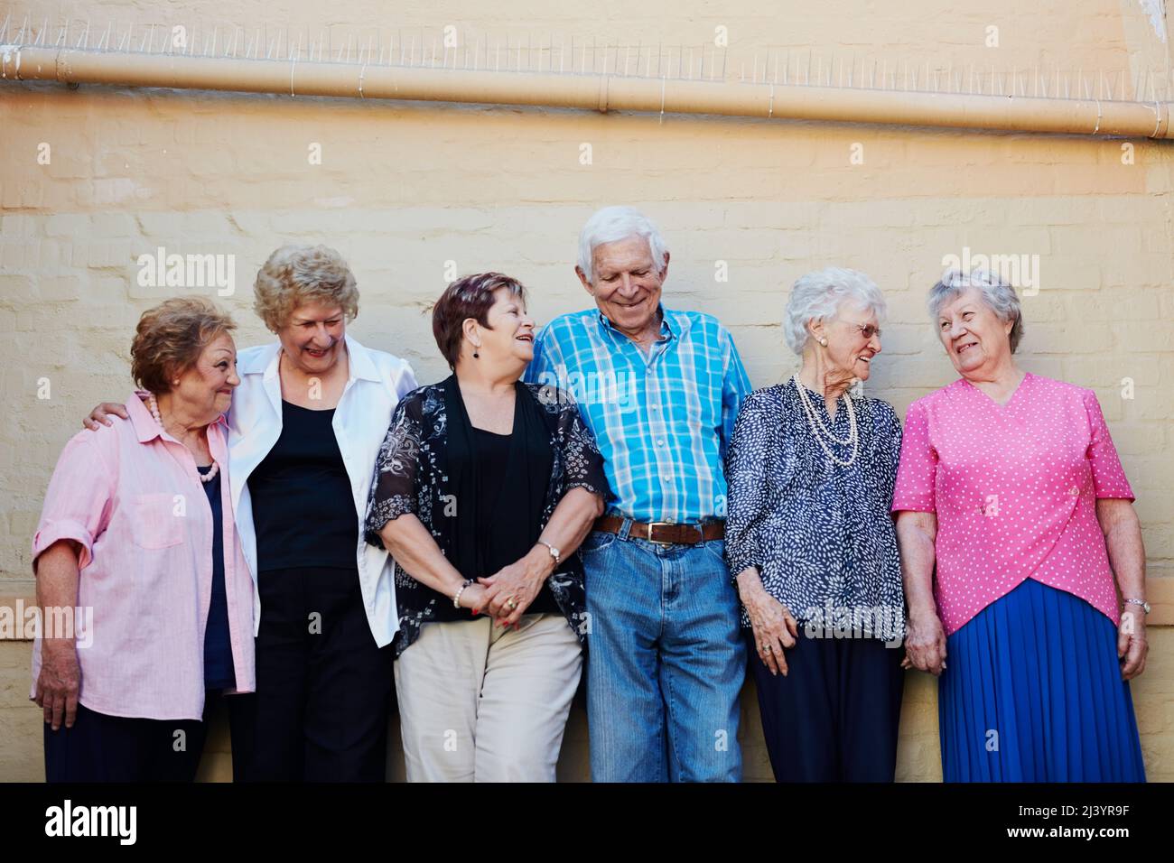 Je älter wir werden, desto mehr genießen wir das Leben. Aufnahme einer Gruppe von Senioren, die draußen an einer Wand stehen. Stockfoto