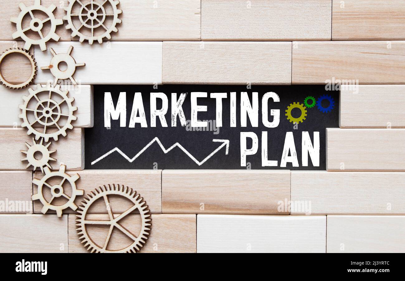 Notizbuch mit Text-Marketingplan auf Tisch mit Kaffee, Rechner und Notizbuch Stockfoto