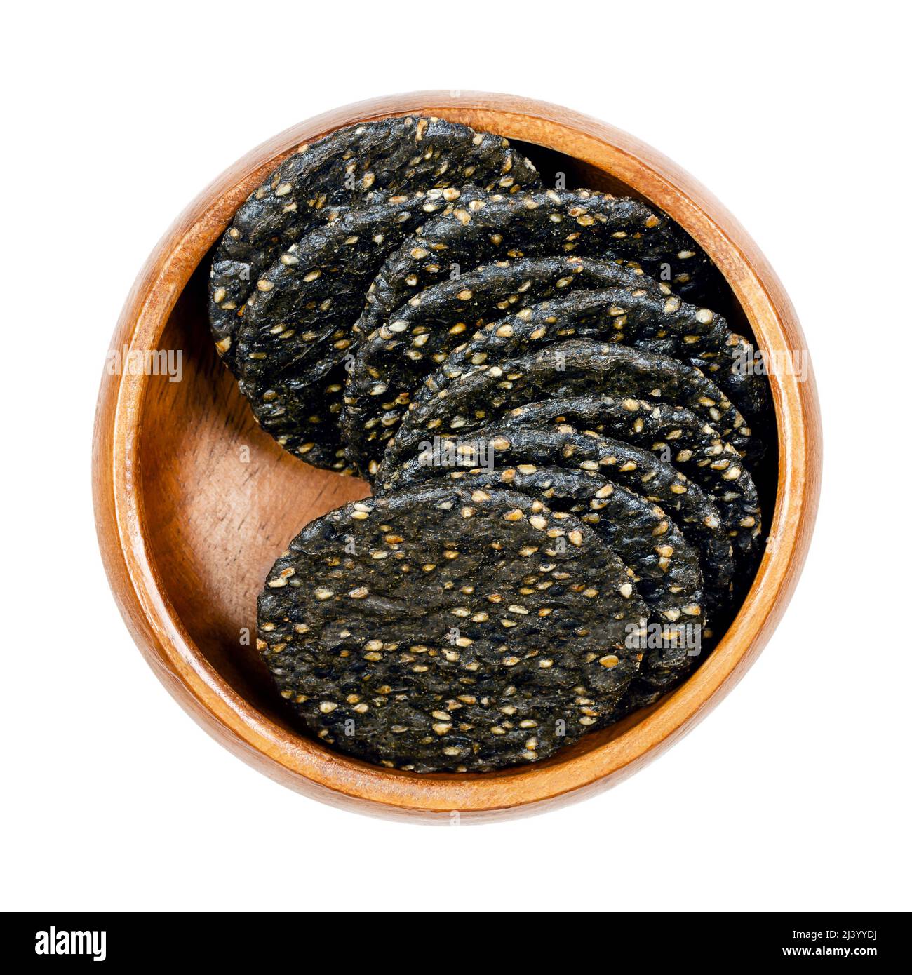 Senbei, japanische Sesamcracker, in einer Holzschale. Knusprige makrobiotische Cracker aus braunem Reis, schwarzen Sesamsamen und Sojasauce. Knackiger Snack. Stockfoto