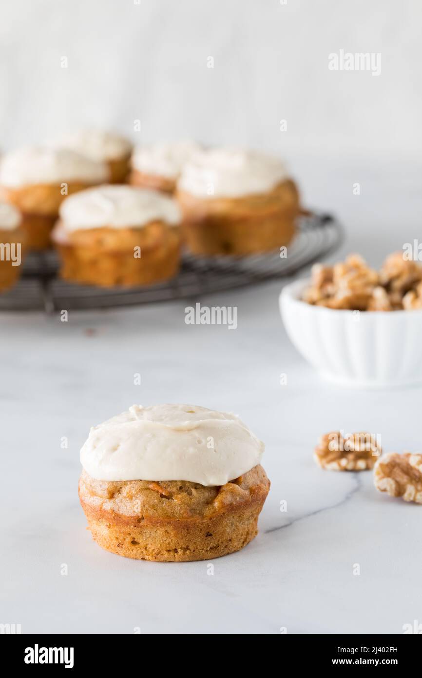 Ein hausgemachter Karottenkuchenmuffin mit Frischkäse-Glasur und andere dahinter. Stockfoto