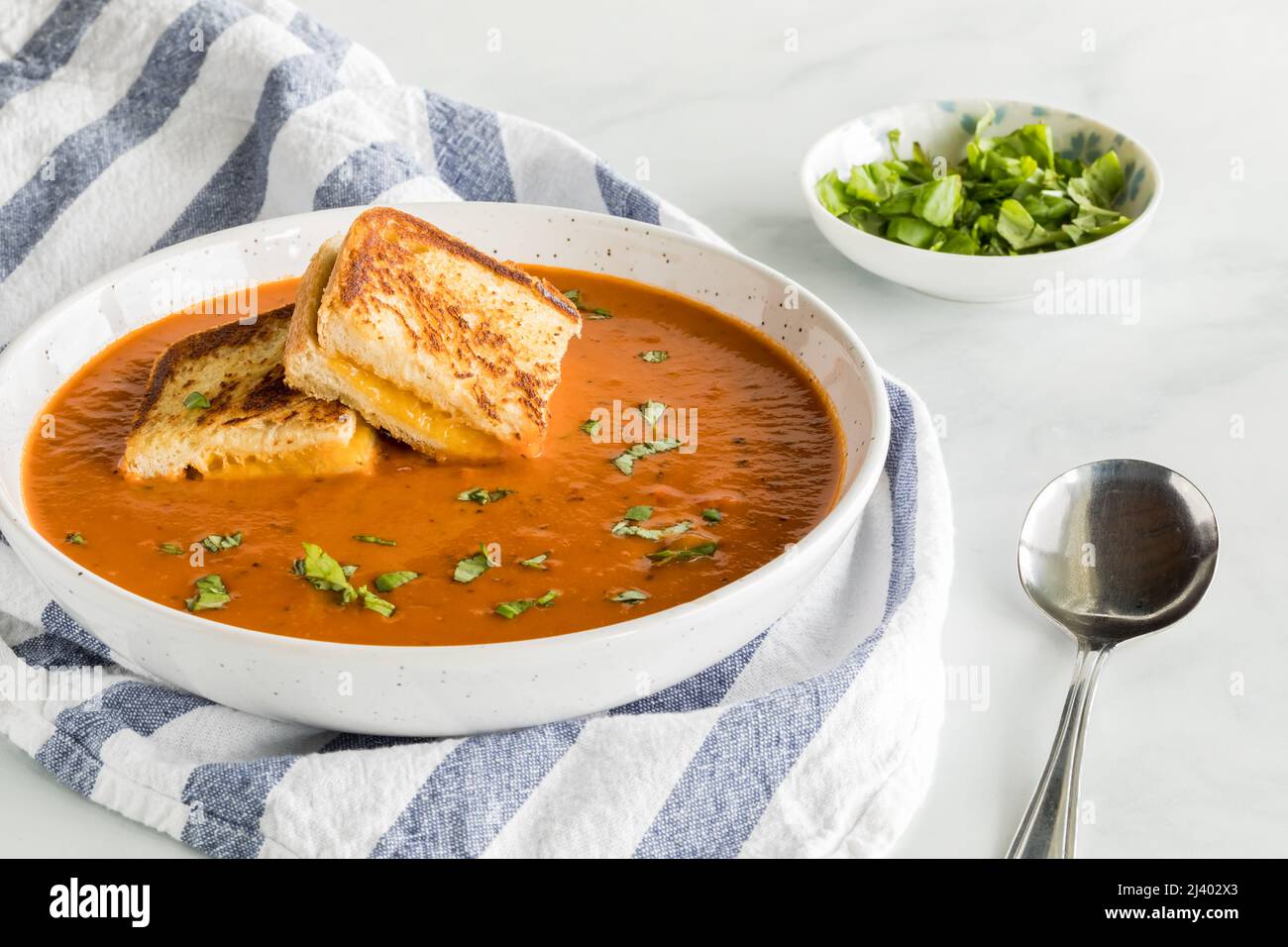 Eine Schüssel Tomatensuppe mit kleinen gegrillten Käsesandwiches darauf. Stockfoto