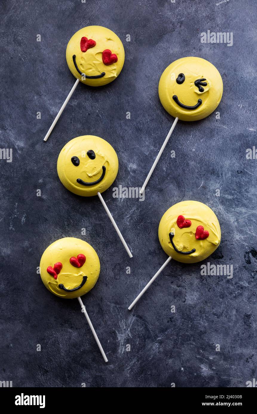 Smiley Face Emoticon Merengue Cookies mit Lollipop-Sticks. Stockfoto