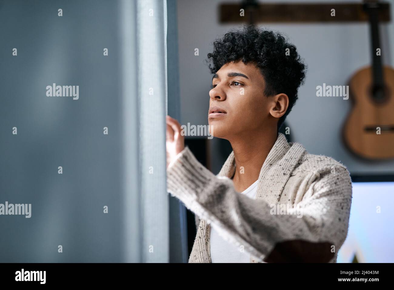 Hallo Welt, vermisst du mich wie Du fehlst mir. Aufnahme eines jungen Mannes, der morgens zu Hause seine Vorhänge im Schlafzimmer öffnete. Stockfoto