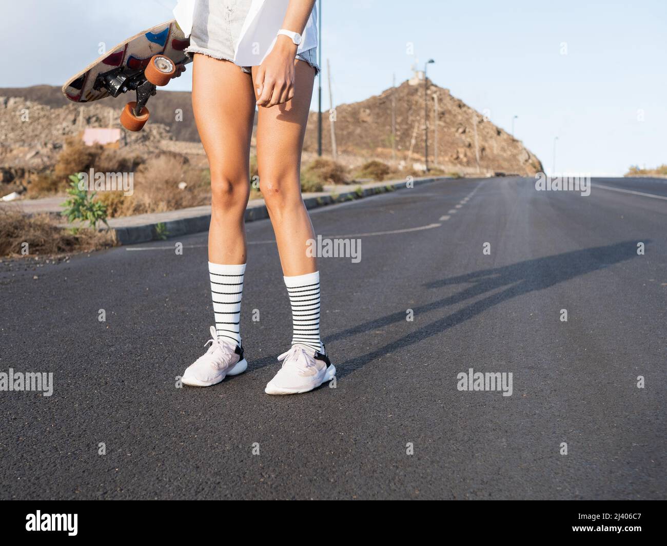 Nicht erkennbares Skatermädchen, das auf der Straße steht Stockfoto