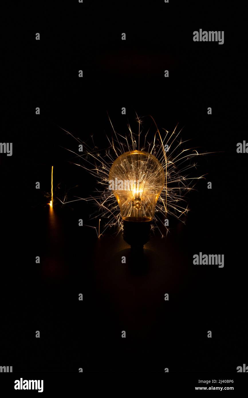 Glühlampe mit Funken auf schwarzem Hintergrund. Stockfoto
