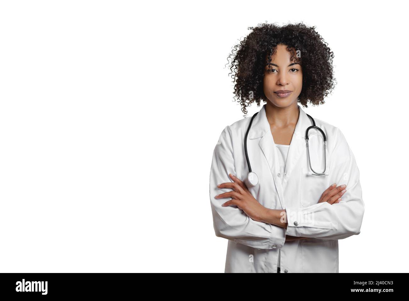 Die lockige afroamerikanische Ärztin trägt eine Uniform und steht mit isolierten Armen auf weißem Hintergrund und blickt auf die Kamera Stockfoto