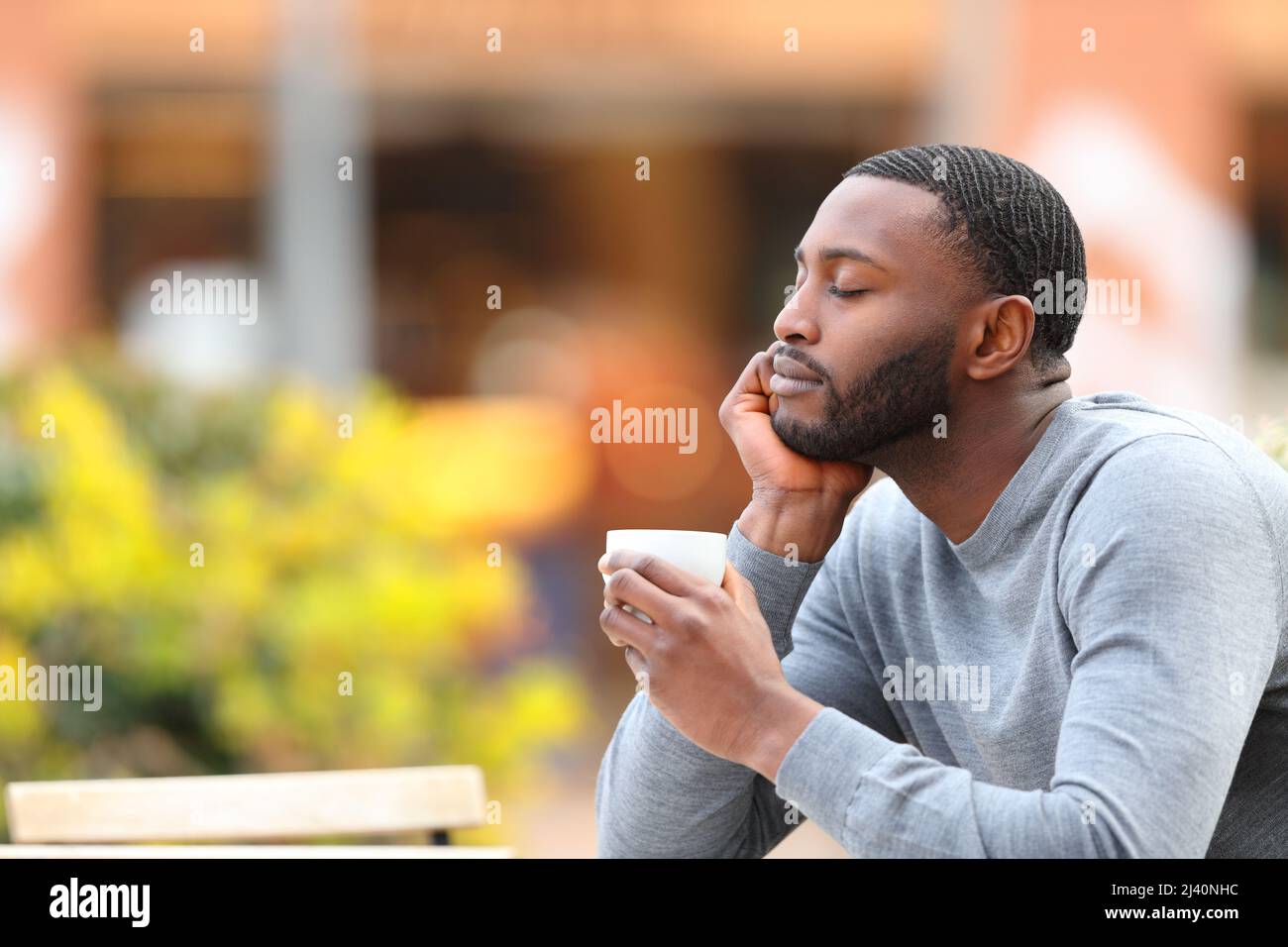 Mann mit schwarzer Haut, der sich ausruhte und auf der Barterrasse einen Kaffee trank Stockfoto