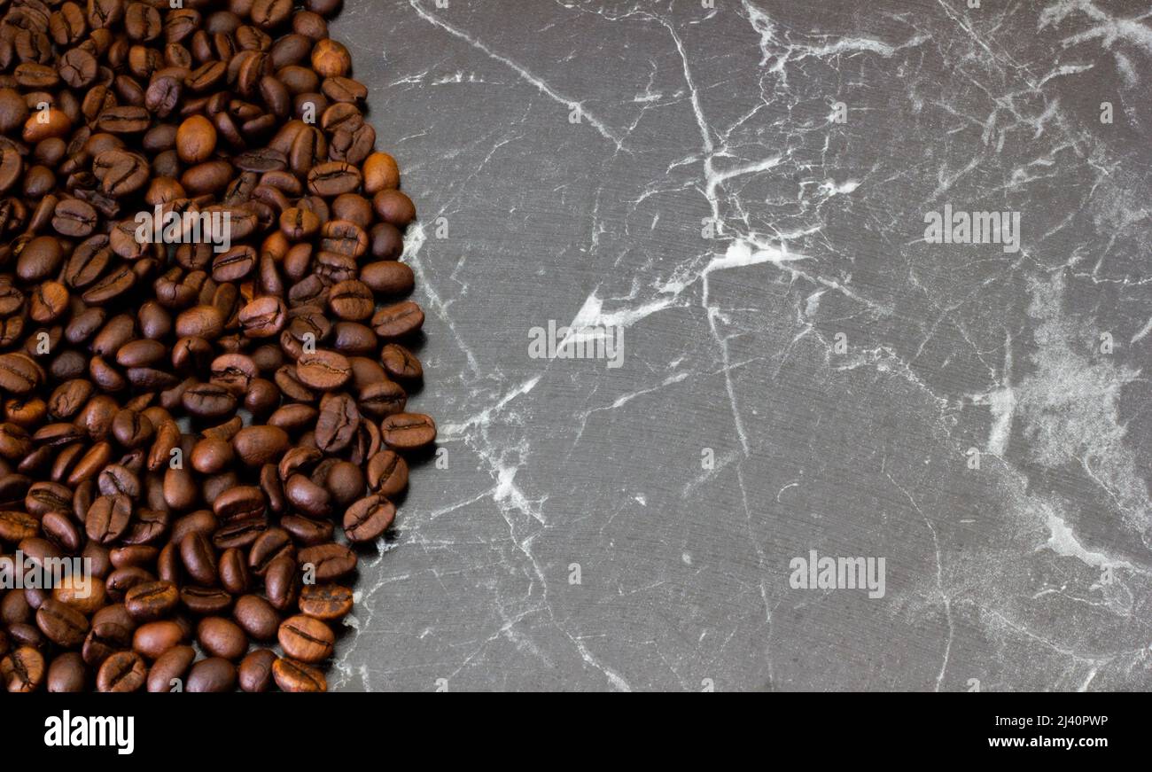 Frisch geröstete Kaffeebohnen von links auf grauem Hintergrund. Kann als Hintergrund oder Textur verwendet werden. Stockfoto