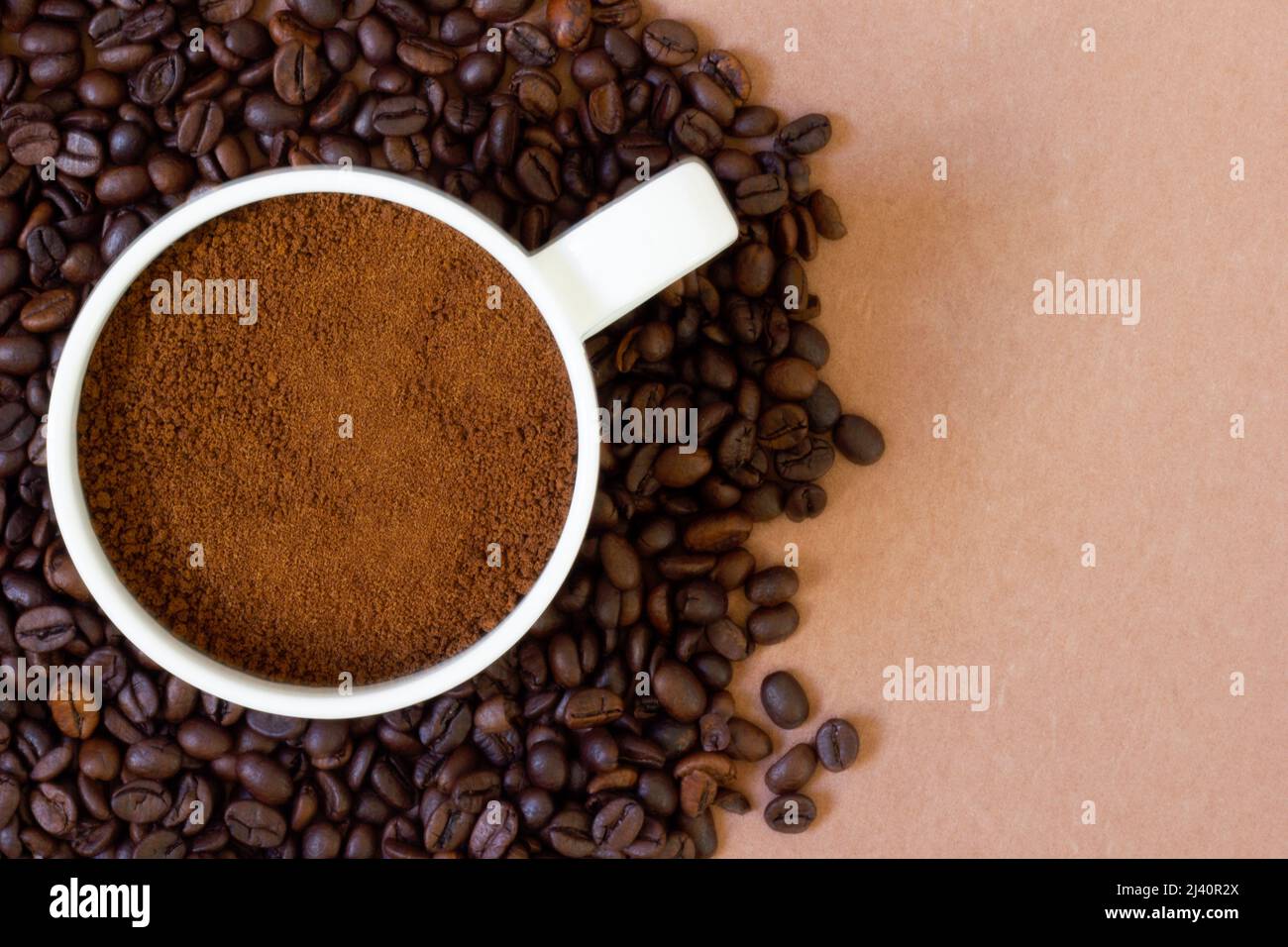 Frisch geröstete Kaffeebohnen auf farbigem Hintergrund und gemahlener Kaffee in einer Tasse darauf. Hintergrund und Textur verfügbar Stockfoto
