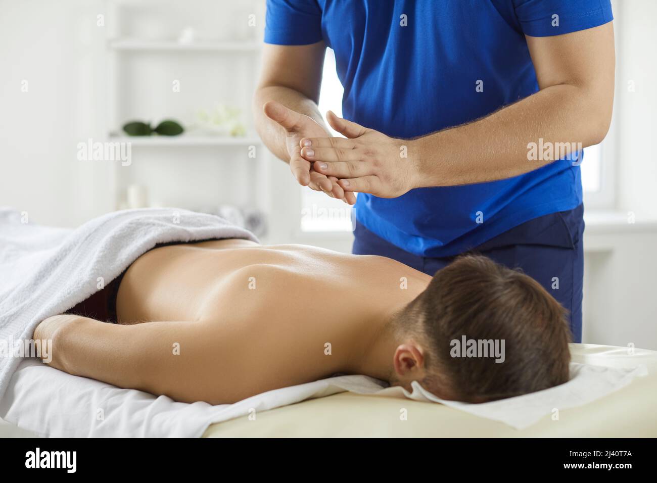 Junger Mann, der sich während der Massage durch professionellen Masseur oder manuellen Therapeuten entspannt Stockfoto