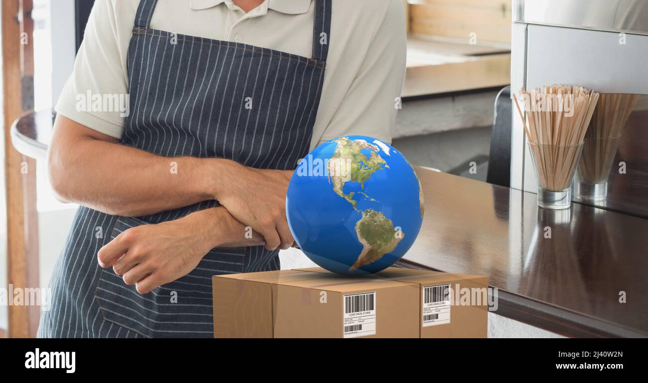 Globe über den Lieferkarton gegen den mittleren Teil einer Person, die Schürze trägt Stockfoto