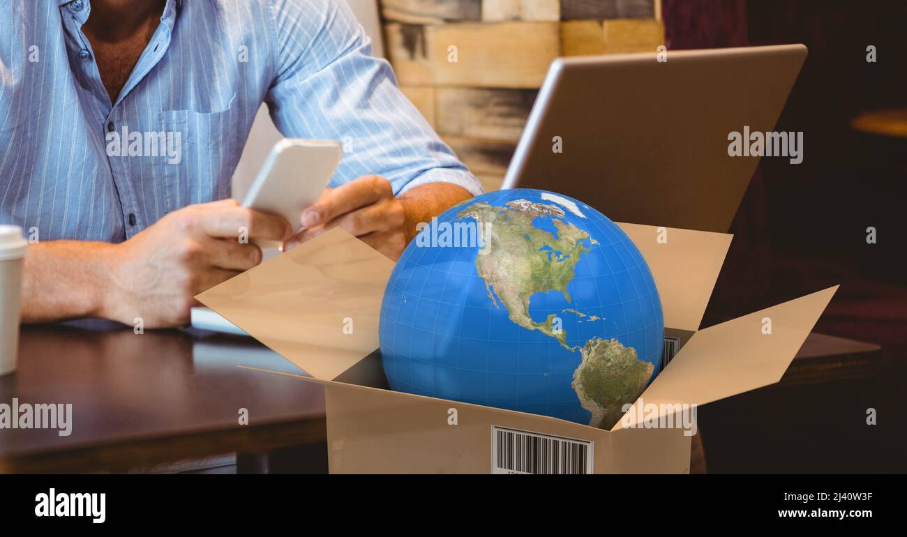 Globe im Lieferkarton gegen den mittleren Teil einer Person, die ein Smartphone in einem Café verwendet Stockfoto