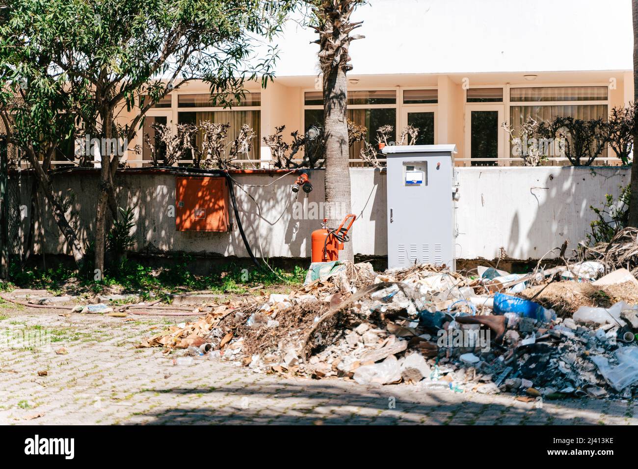 Müllschutt stapelt sich vor dem Wohnhaus. Sicherungskasten mit Abfall umgeben. Müll im Hausmüll, der außerhalb des Wohnbereichs verstreut ist Stockfoto