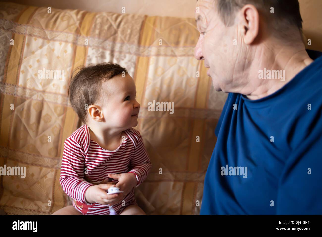 Ein lächelndes Baby und ihr Großvater spielen zusammen Stockfoto