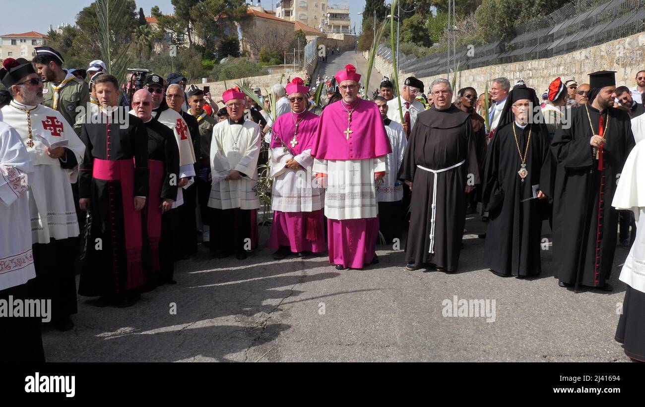 Der lateinische Patriarch von Jerusalem Pierbattista Pizzaballa (C) und Mitglieder des Klerus nehmen an der jahrhundertealten Palmsonntagsprozession Teil, die am 10. April 2022 in Jerusalem, Israel, vom Ölberg in die Altstadt führt. Der Palmsonntag erinnert an den Eintritt Jesu Christi in Jerusalem, der mit Palmzweigen geehrt wurde, und markiert den Beginn der vorösterlichen Karwoche. Stockfoto