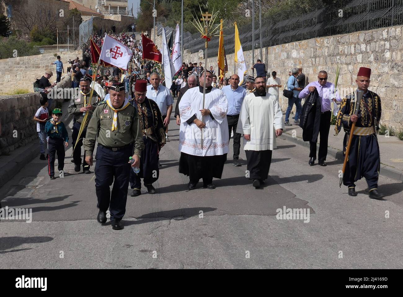Ein Mitglied des Klerus hält ein Kreuz, während Christen an der jahrhundertealten Palmsonntagsprozession teilnehmen, die am 10. April 2022 in Jerusalem, Israel, vom Ölberg in die Altstadt geht. Der Palmsonntag erinnert an den Eintritt Jesu Christi in Jerusalem, der mit Palmzweigen geehrt wurde, und markiert den Beginn der vorösterlichen Karwoche. Stockfoto