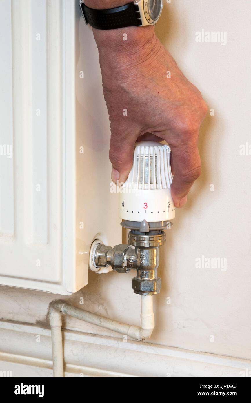 Drehen Sie die Heizung herunter, um Geld zu sparen. Verwendung eines Thermostatventils, das an einem Raumheizkörper angebracht ist. Stockfoto