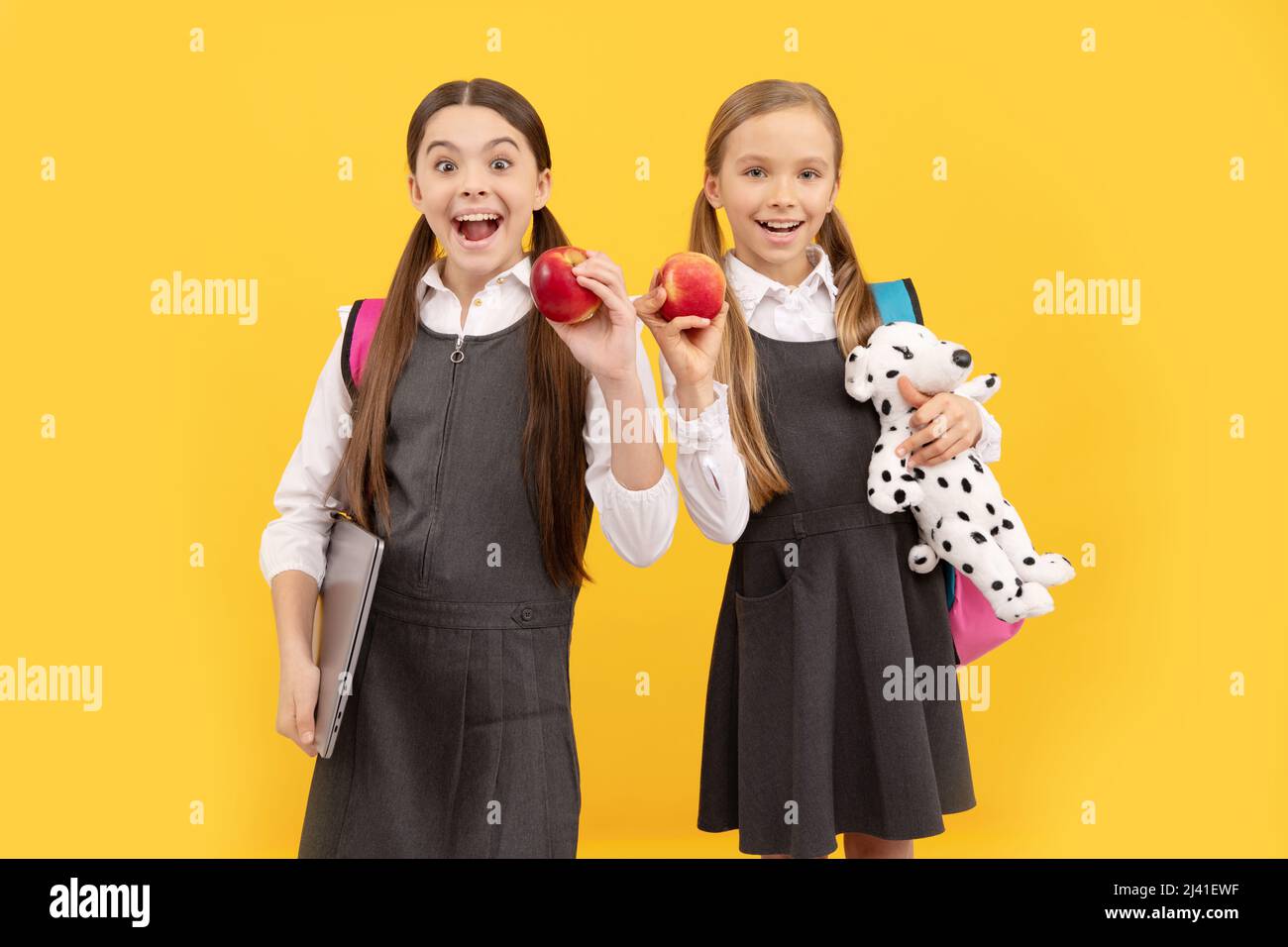 Schulkinder in formellen Uniformen halten die Münder offen von Überraschung mit natürlichen Äpfeln, gesunder Ernährung Stockfoto