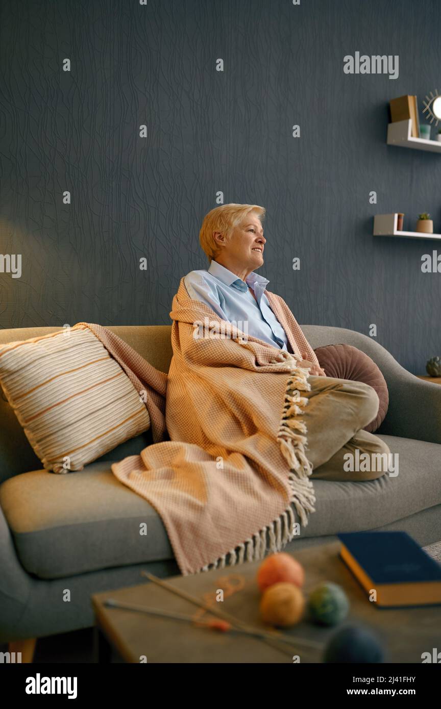 Zufriedene alte Frau in Decke eingehüllt entspannend Stockfoto