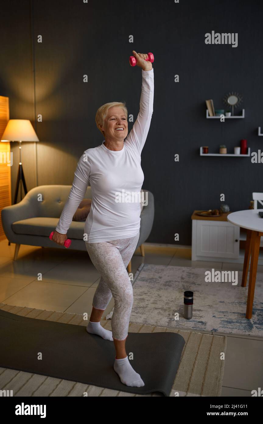 Pensionierte Frau genießen Heimfitness im Wohnzimmer Stockfoto