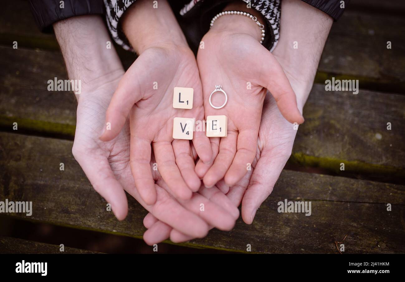 Engagement Paare cupped Hände mit Ring und scrabble Stücke Schreibweise Liebe Stockfoto