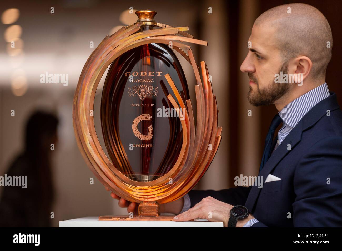 London, Großbritannien. 11. April 2022. Diego Lanza, Bonhams, Senior Whisky Specialist, präsentiert einen „Godet-Origine“, einen Jerobeam von Godet-Origine, die Nummer eins von drei Flaschen. Sie wird von einem soliden Kupferskulptur-Ständer und einer kupferveredelten Glaspipette von Romain de Souza (Est. £15.000-20.000). Vorschau auf „The Old, The Rare and the Only“, eine Einzelbesitzersammlung von seltenem Whisky, Cognac und armagnac. Mehr als 400 Single Malts und 100 Flaschen Cognac und armagnac aus den Jahren 1920s bis 2000s werden am 13. April in der Galerie Bonhams New Bond Street zum Verkauf angeboten. Kredit: Stephen Chung / Alamy Live Nachrichten Stockfoto