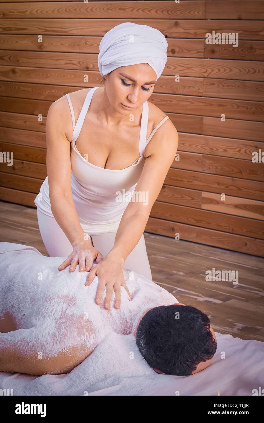 Eine Heilerin führt ein Ritual mit Salz durch, reibt den Rücken eines Lügenmenschen mit Salz. Entspannung. Stockfoto