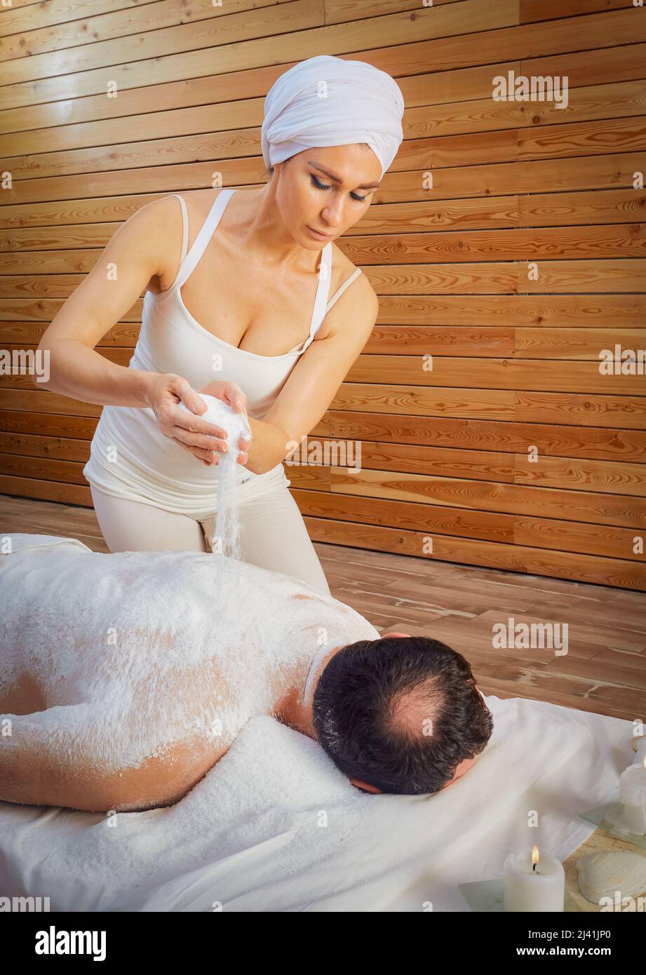 Eine Heilerin führt ein Ritual mit Salz durch, gießt Salz auf den Rücken eines Lügenmannes. Entspannung. Stockfoto