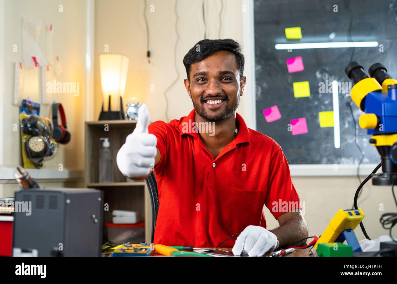 Glücklicher Reparaturmann, der die Daumen nach oben zeigt, indem er die Kamera in der mobilen Reparaturwerkstatt anschaut - Konzept der Empfehlung, Genehmigung und Erfolg klein Stockfoto