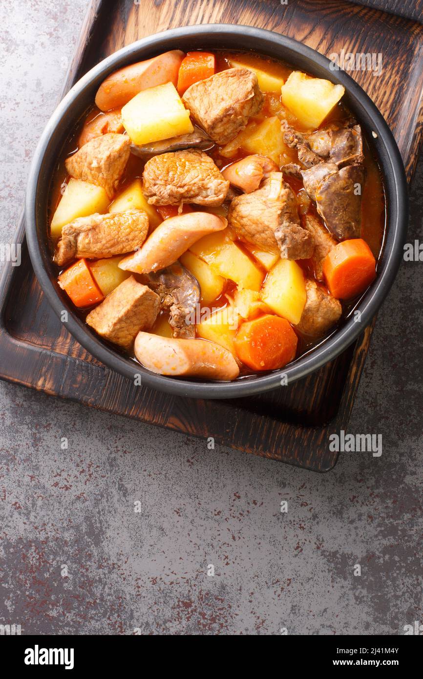 Filipino Menudo ist ein herzhafter und schmackhafter Schweinestau, der aus frischen Tomaten, Kartoffeln und Karotten in der Nähe auf dem Teller auf dem Tisch zubereitet wird. Vertikale Draufsicht von Stockfoto