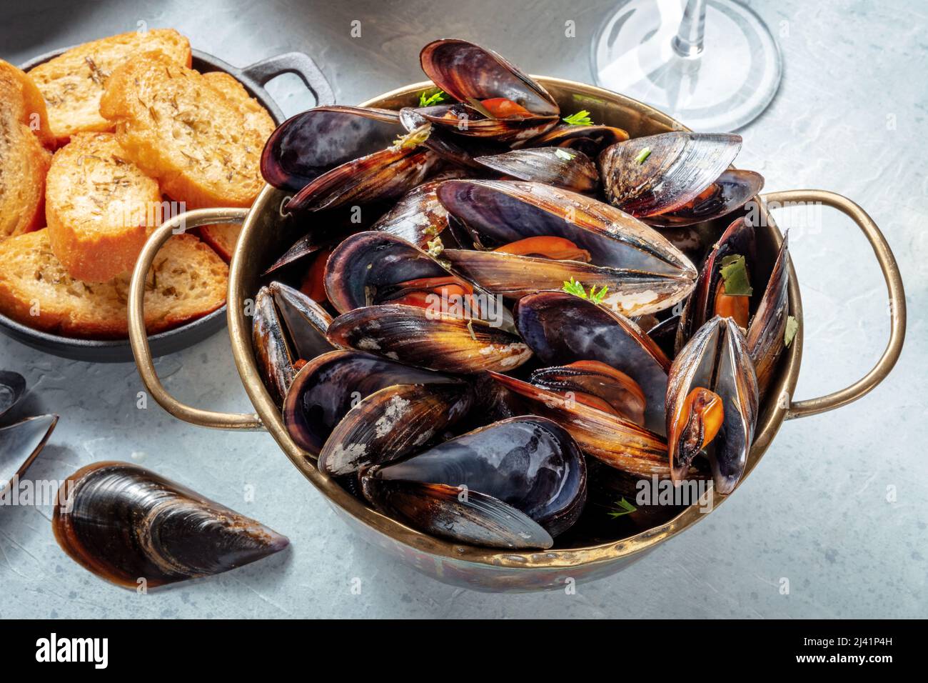 Gekochte Muscheln in einer Kupferpfanne, belgische oder französische Küche in einem Restaurant mit geröstetem Brot Stockfoto