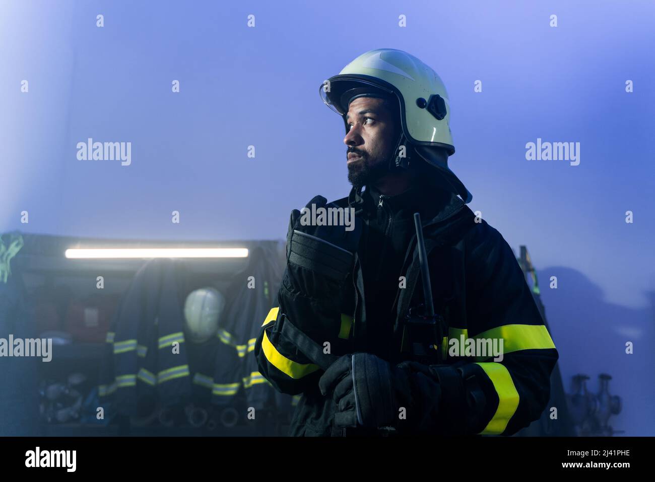 Junger afroamerikanischer Feuerwehrmann in der Feuerwache bei Nacht. Stockfoto