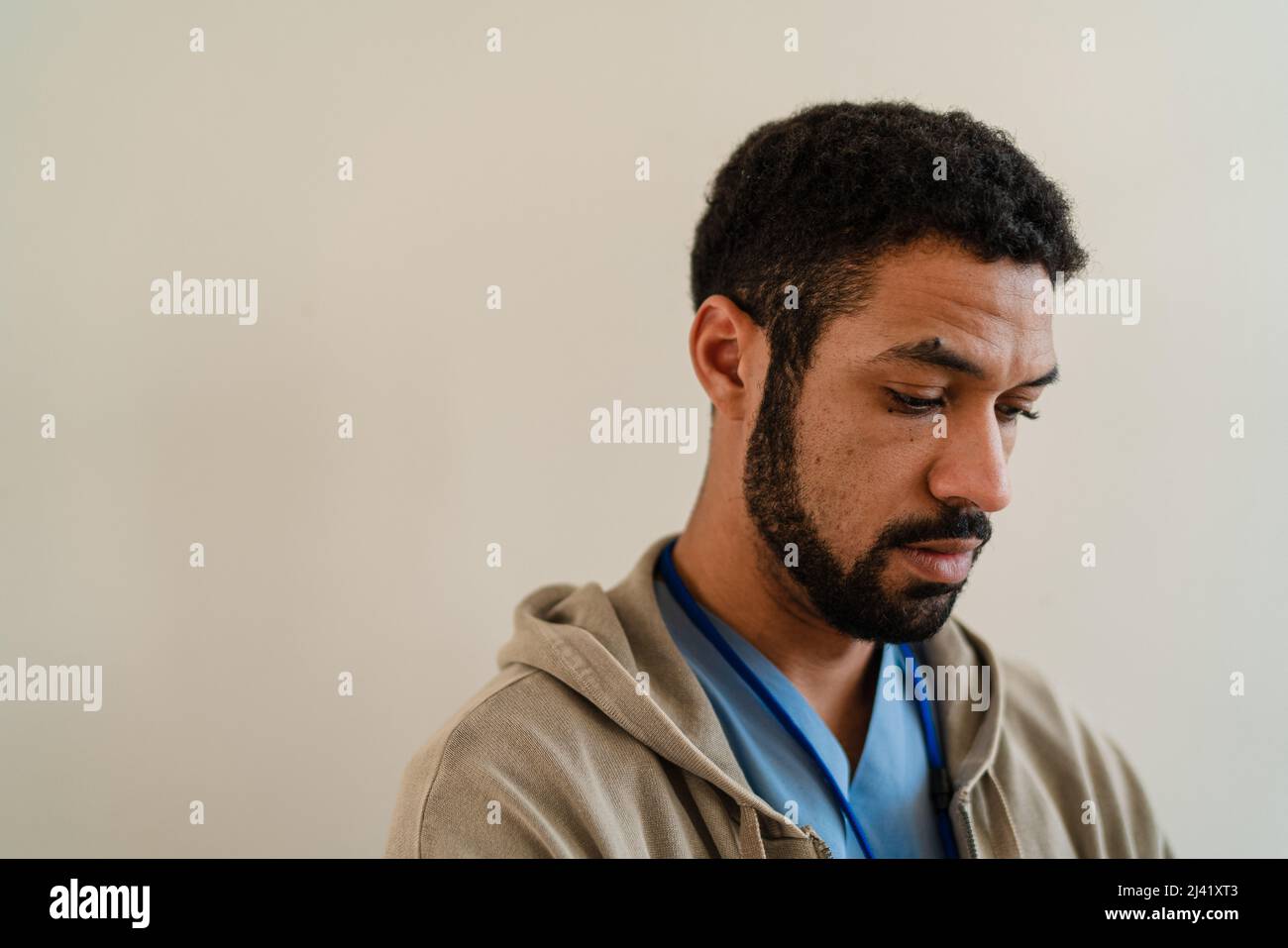 Deprimierter junger männlicher Arzt oder Pflegekraft auf beigem Hintergrund. Stockfoto