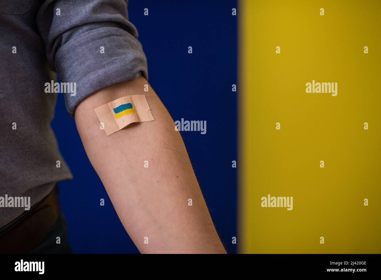 Blutspender mit Verband, nachdem er Blut auf ukrainischem Hintergrund gegeben hat. Stockfoto