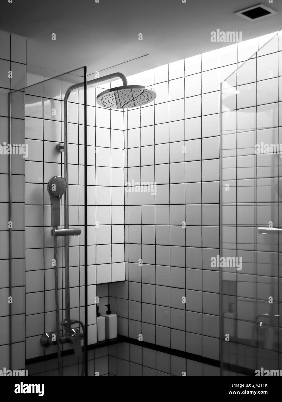 Schwarz-weiße Kacheln Wand, das Innere der modernen Dusche Raum-Box im Bad mit Overhead-Regendusche in Glastür Trennwand, vertikale s Stockfoto