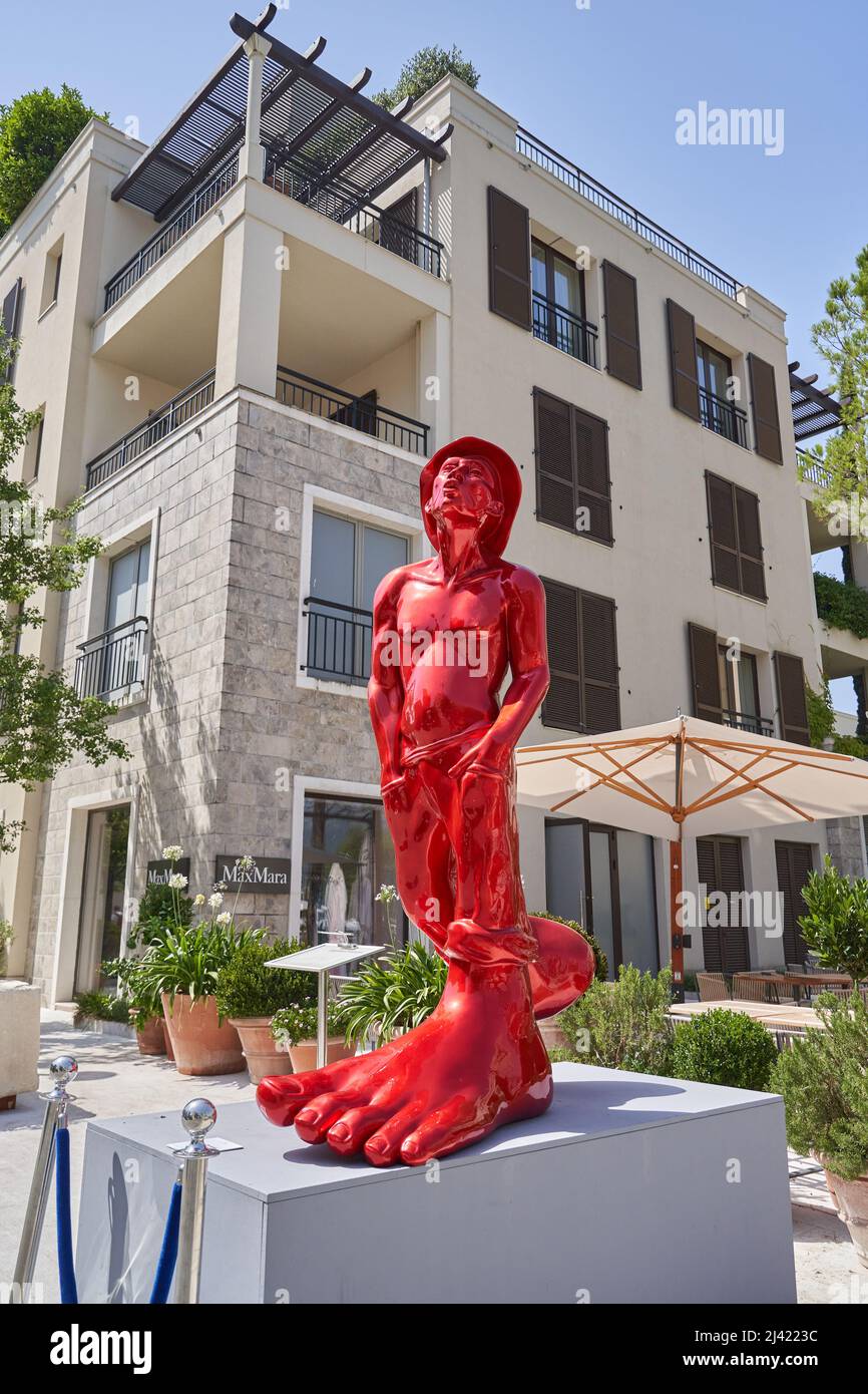 TIVAT, MONTENEGRO - 29. JULI 2021: Rote Skulptur eines Mannes mit großen Beinen in der Stadt, Installation moderner Kunst Stockfoto