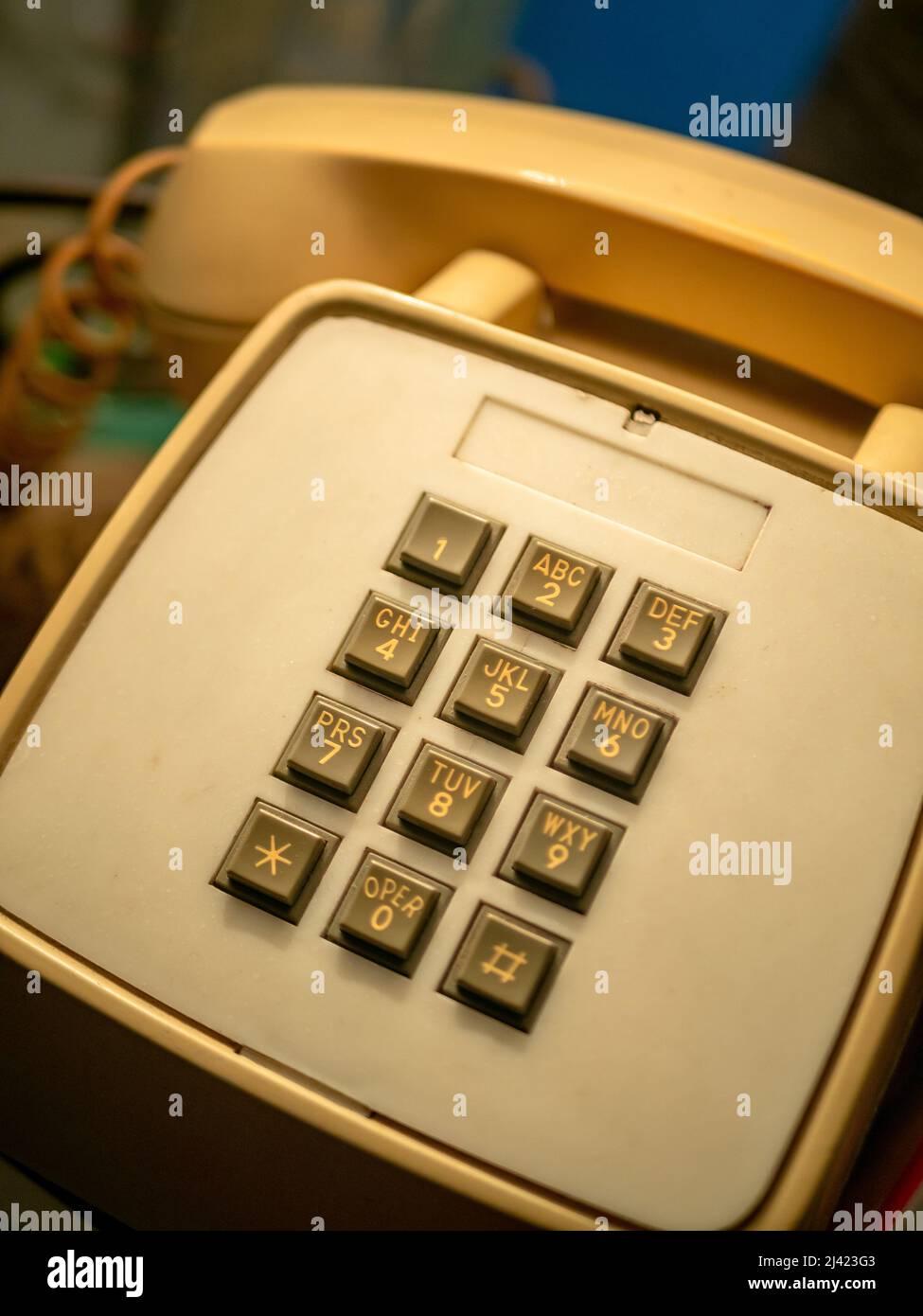Altes Telefon mit einer cremefarbenen Tastatur auf einem Tisch auf einigen Büchern Stockfoto